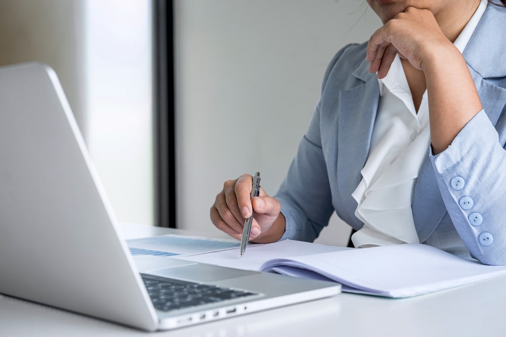 Business woman looking at laptop and notebook