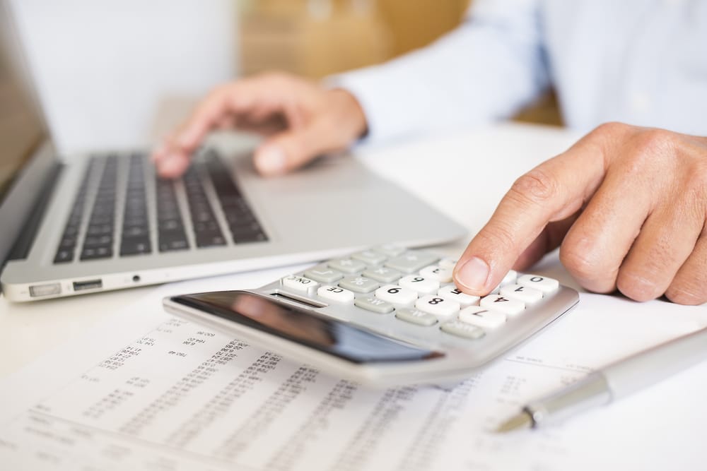 Close-up of hands using laptop and calculator