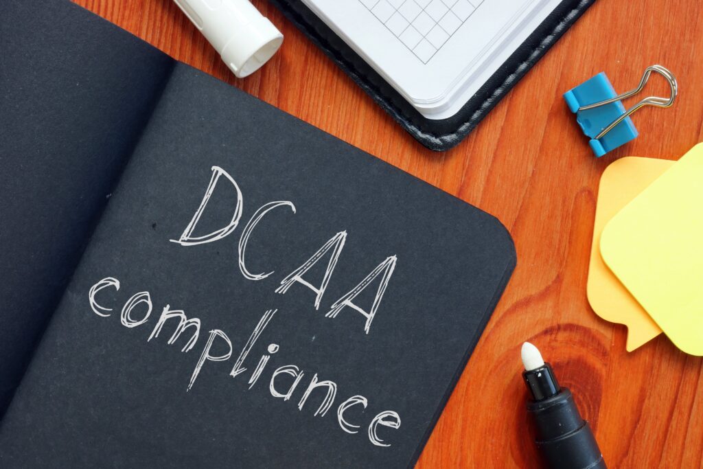 Data compliance written in black notebook beside post-its, clip, marker, etc