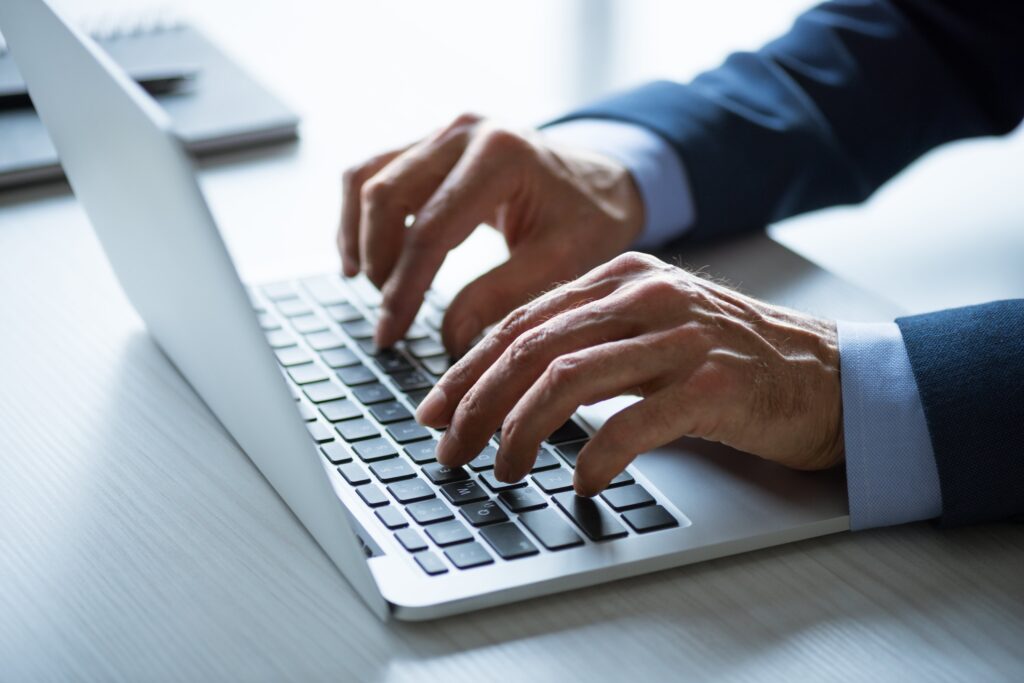 Close-up of hands typing on laptop