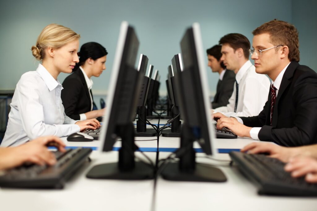 Employees looking at computers, their desks facing each other