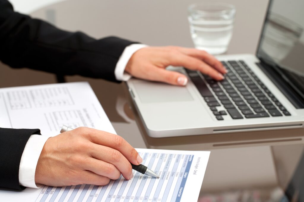 Female employee reviewing document and typing on laptop