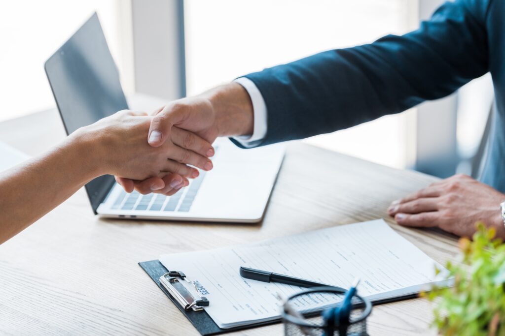 Professional handshake over laptop and clipboard