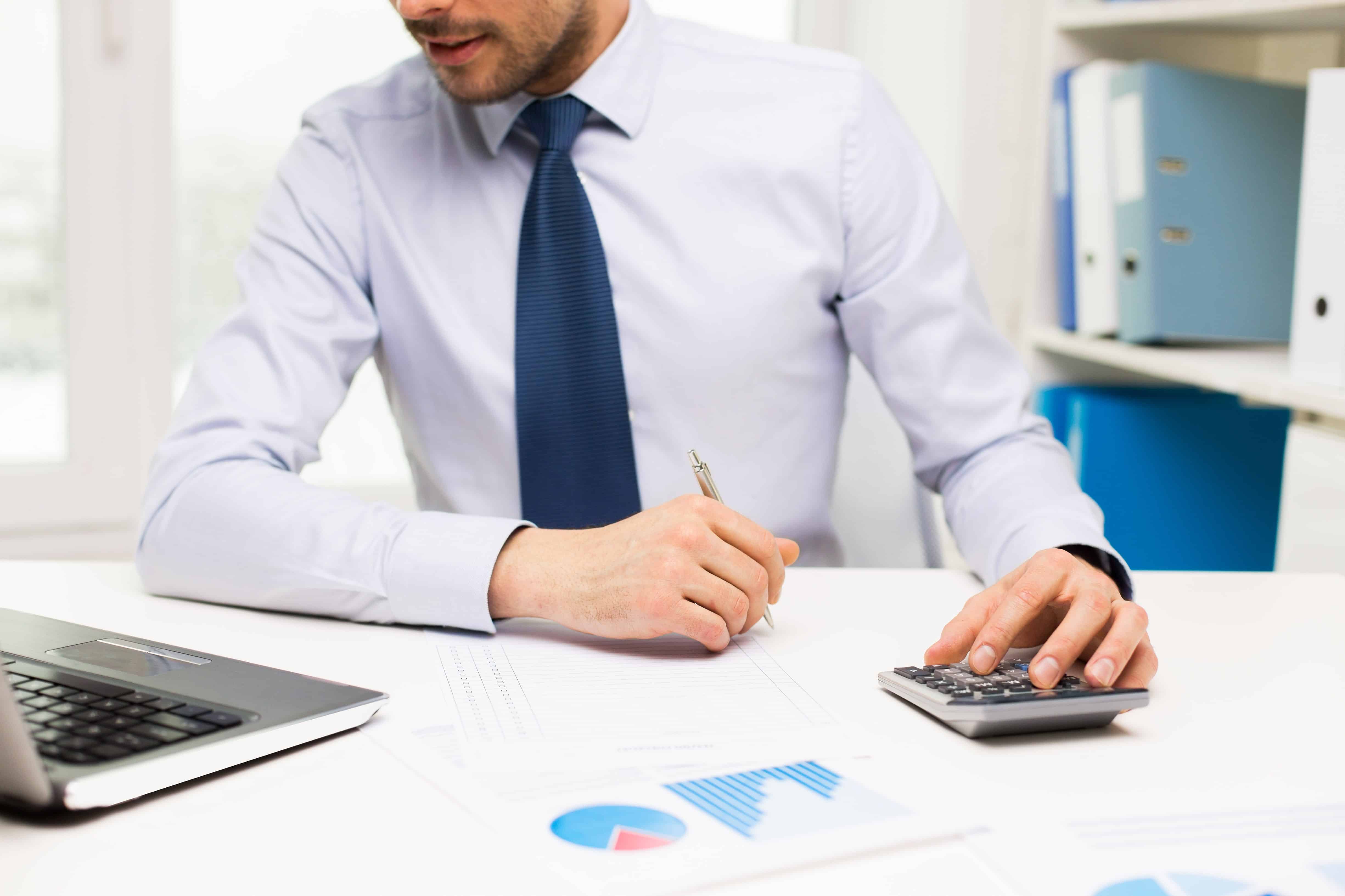 Young employee using laptop and calculator