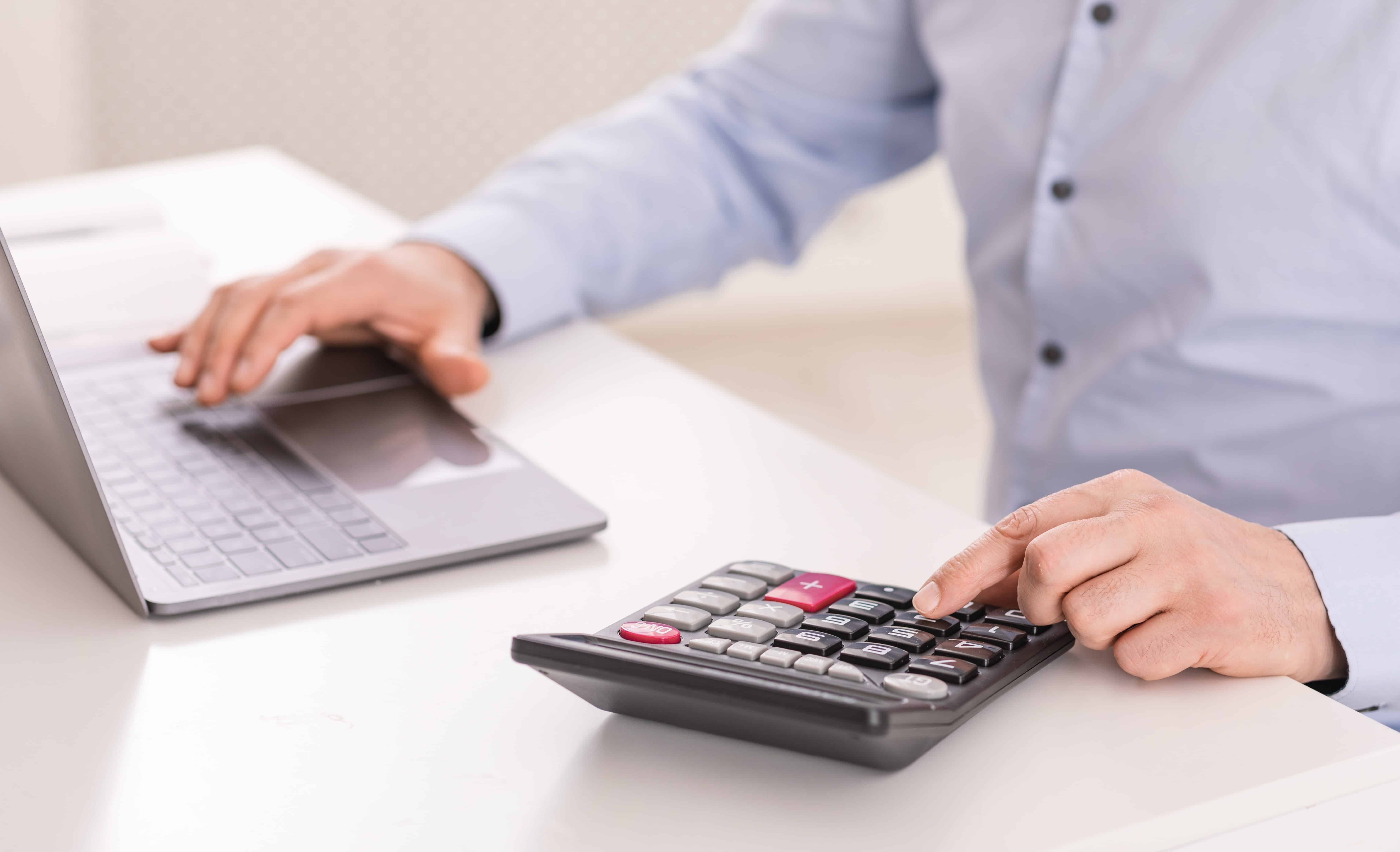 Close-up of employee using laptop and calculator