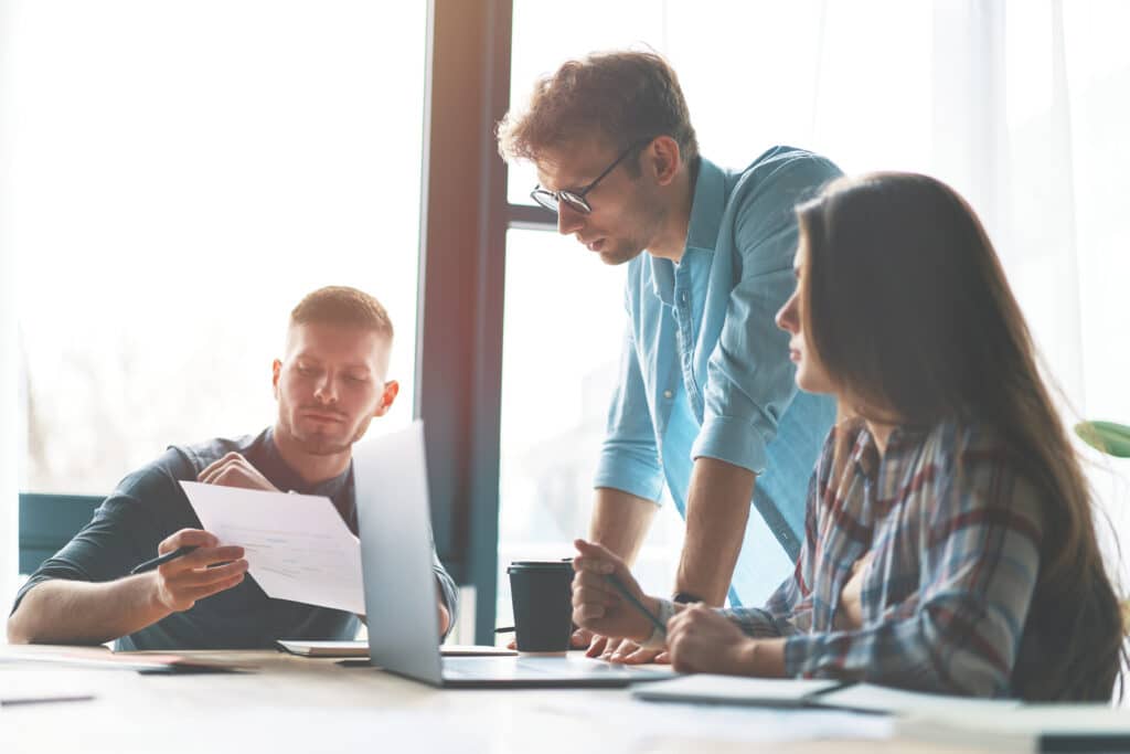 Three young employees talking while looking at paper, small business