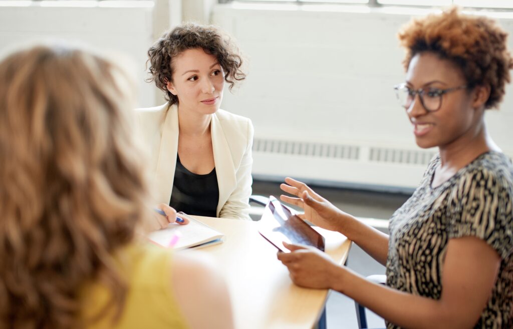 Three young female employees talking in meeting
