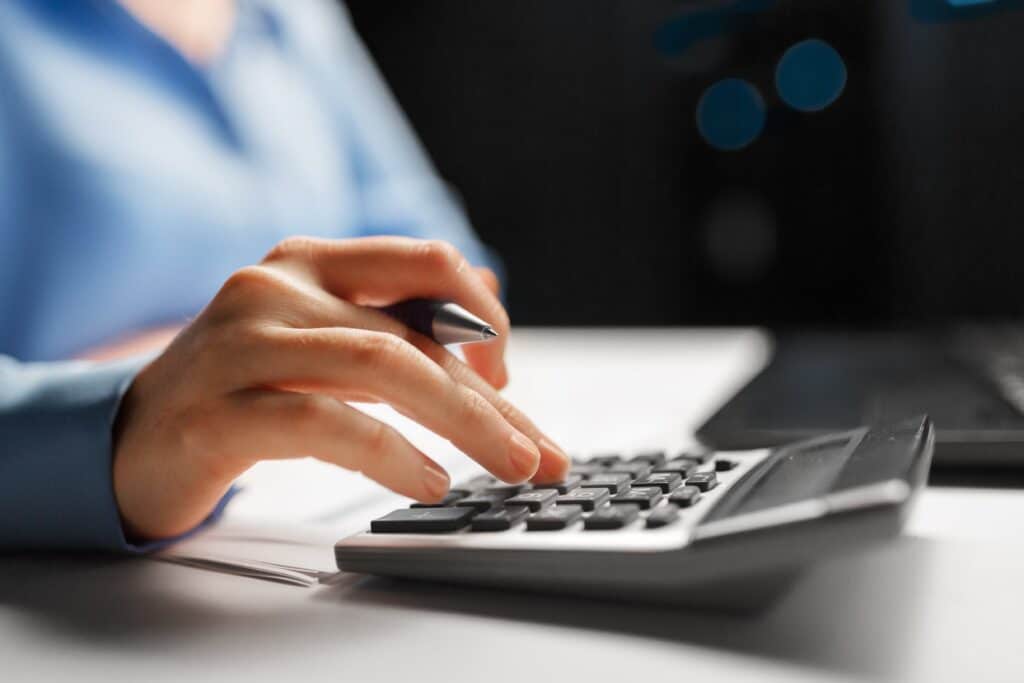 close-up of female employee typing on calculator